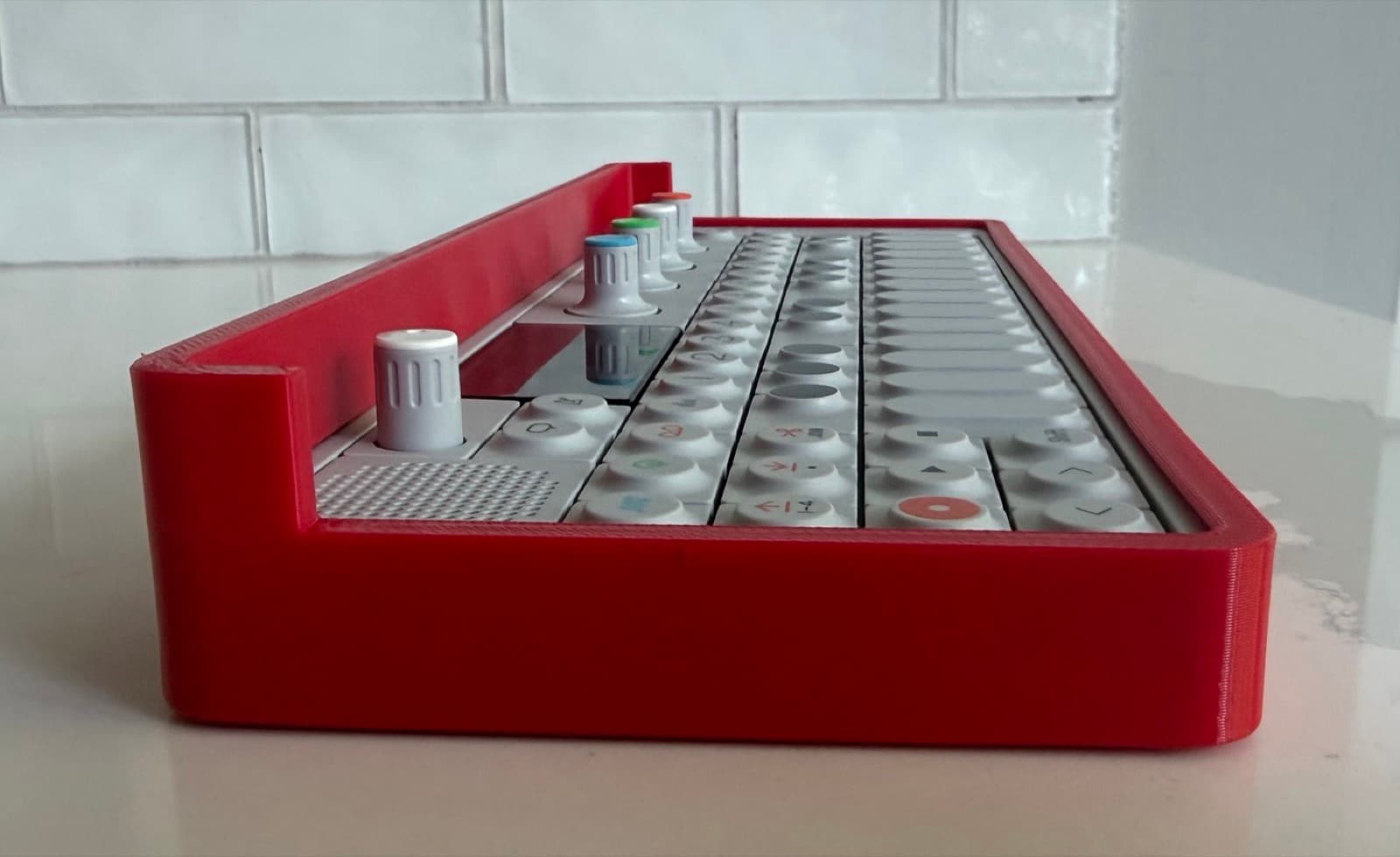 Profile view showing the bumper rim standing proud of the OP-1's face